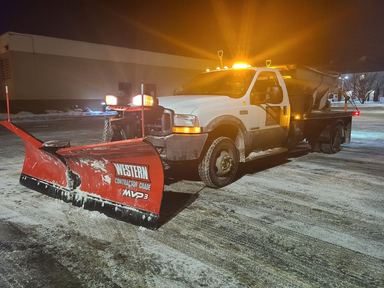 Norwest snow plow clearing a commercial property at night